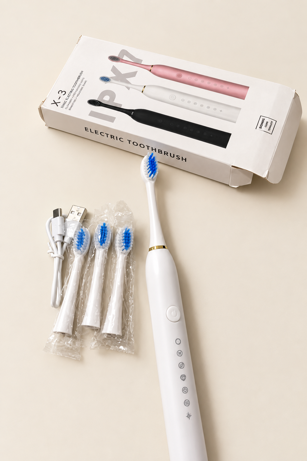 Brosse à dents électrique blanche avec ses têtes de rechange et son câble USB